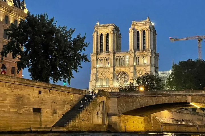 Notre-Dame lit at dusk above the quay